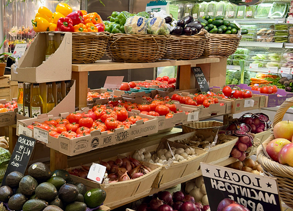 Frisches Obst und Gemuese wie Tomaten, Paprika, Avocados, Zwiebeln und Salate in einem Markt. Ideal fuer eine gesunde und alltagstaugliche Ernaehrung, wie sie auf ernaehrungsberatung.fit vermittelt wird.